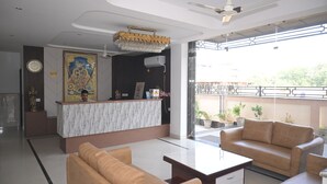 Una hall d'albergo moderna con reception, zona salotto e ampie finestre.