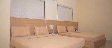 A hotel room with two beds, a ceiling fan, and a wall-mounted air conditioner.