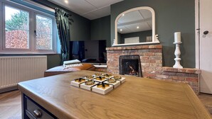 A room with a fireplace, a dining table with a box of bracelets, a mirror, and a window with curtains. - Hill House - UK49727 (King&rsquo;s Lynn)