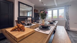 A dining area with a long wooden table set for a meal, a mirror above the table, and a window with curtains. - Hill House - UK49727 (King&rsquo;s Lynn)