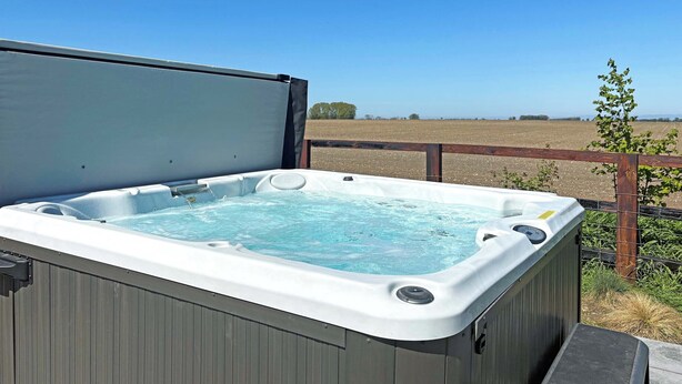 A hot tub with a wooden deck and a view of a field. - Hill House - UK49727 (King&rsquo;s Lynn)