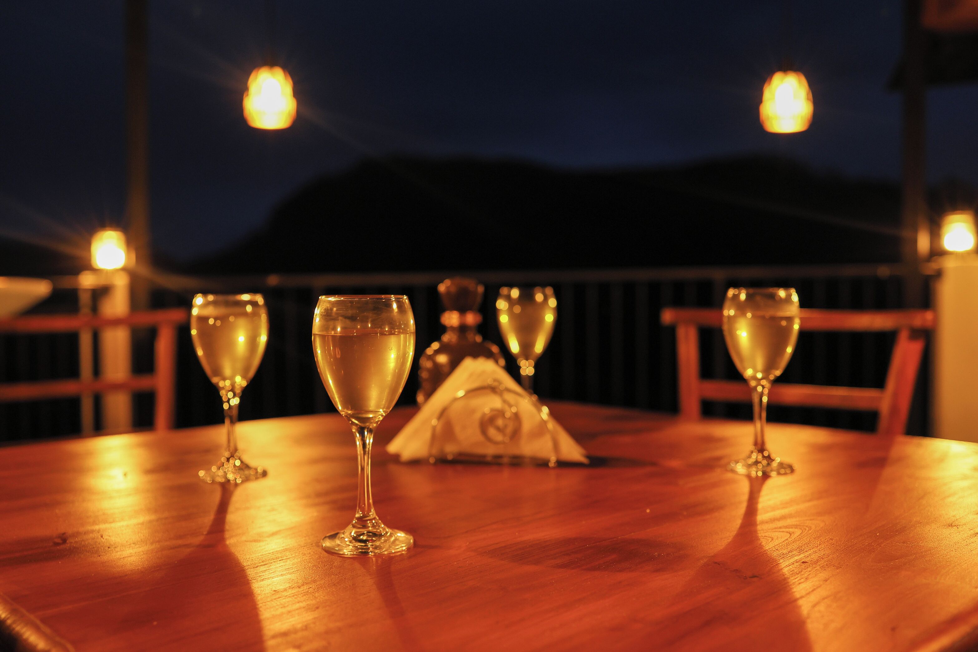 Une table en bois sur laquelle sont posés quatre verres contenant un liquide transparent, probablement du vin, et un objet décoratif au centre.