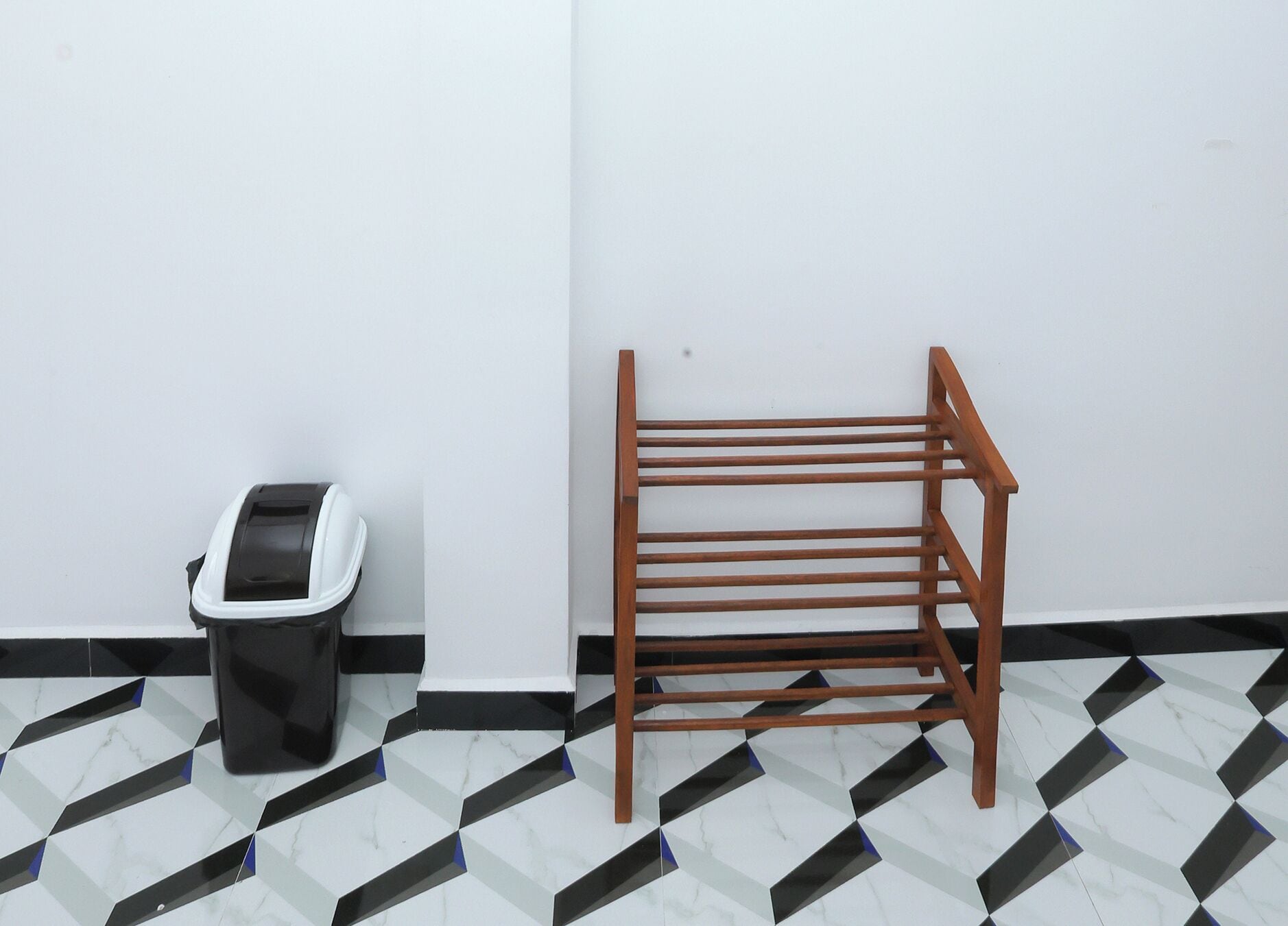 Ein Zimmer mit Fliesenboden, einem Holzstuhl und einem Mülleimer.