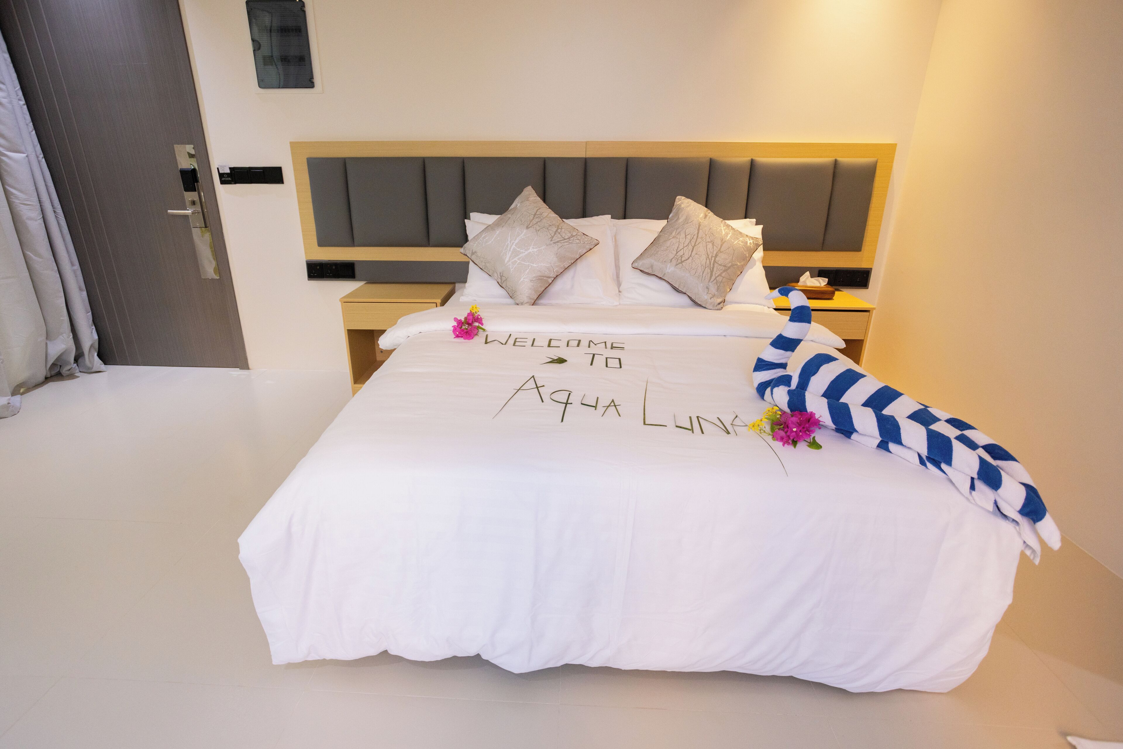Un lit bien fait, agrémenté d’un tapis d’entrée, de coussins et d’un objet décoratif.