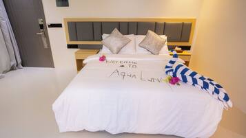 Un lit bien fait, agrémenté d’un tapis d’entrée, de coussins et d’un objet décoratif.