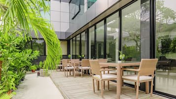 Un área de estar al aire libre con mobiliario de mimbre y plantas en macetas.