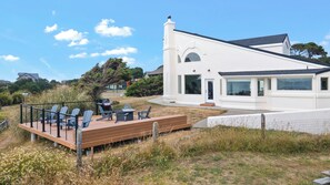 A modern house with a deck, outdoor seating, and a large window overlooking a garden.