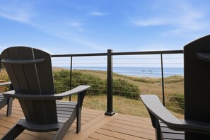 A deck with two Adirondack chairs facing a coastal view.