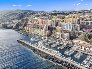 A coastal cityscape with a marina filled with boats, surrounded by residential buildings and hills in the background. - Oceanview Apartment with Balcony (Radazul Bajo)
