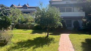 A two-story building with a brick pathway leading to the entrance, surrounded by greenery and a clear blue sky. - Mete 3 Villa İçmeler Weekly Daily Rentals (Marmaris)
