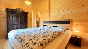 Puupaneloitu makuuhuone, jossa on sänky, yöpöytä ja riippuvalaisin.