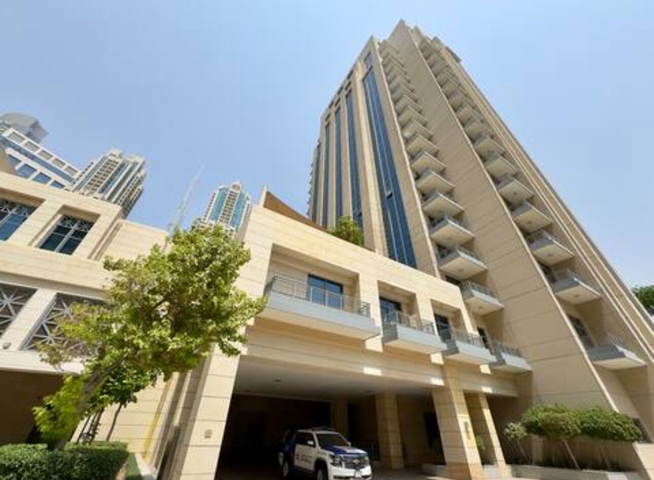 A high-rise building with multiple balconies and a parking garage.