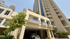 Un edificio de gran altura con varios balcones y un estacionamiento.