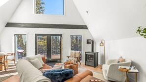 A cozy loft-style living room with a large window, a fireplace, and a comfortable seating area. - Sauna, Hot Tub, Theater, A Frame near Breckenridge (Fairplay)