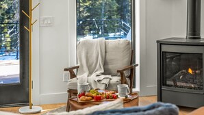 A cozy living room with a fireplace, a comfortable chair, and a table with snacks. - Sauna, Hot Tub, Theater, A Frame near Breckenridge (Fairplay)