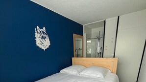 A neatly made bed in a room with a blue wall and a wooden headboard. - 8/10 people at the foot of the slopes La Plagne Centre (La Plagne Tarentaise)