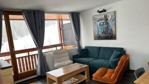 A cozy living room with a teal sofa, orange armchairs, a wooden coffee table, and a painting of a blue car on the wall. - 8/10 people at the foot of the slopes La Plagne Centre (La Plagne Tarentaise)