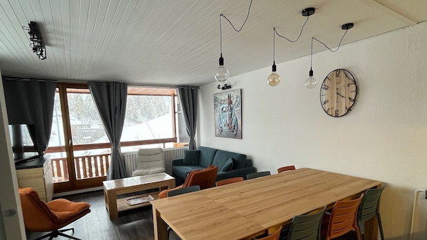 A modern living room with a wooden dining table, orange chairs, a blue sofa, and a large window with curtains. - 8/10 people at the foot of the slopes La Plagne Centre (La Plagne Tarentaise)