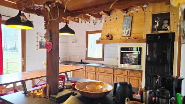 Une cuisine rustique avec des meubles de rangement en bois, un réfrigérateur noir et une table à manger en bois.
