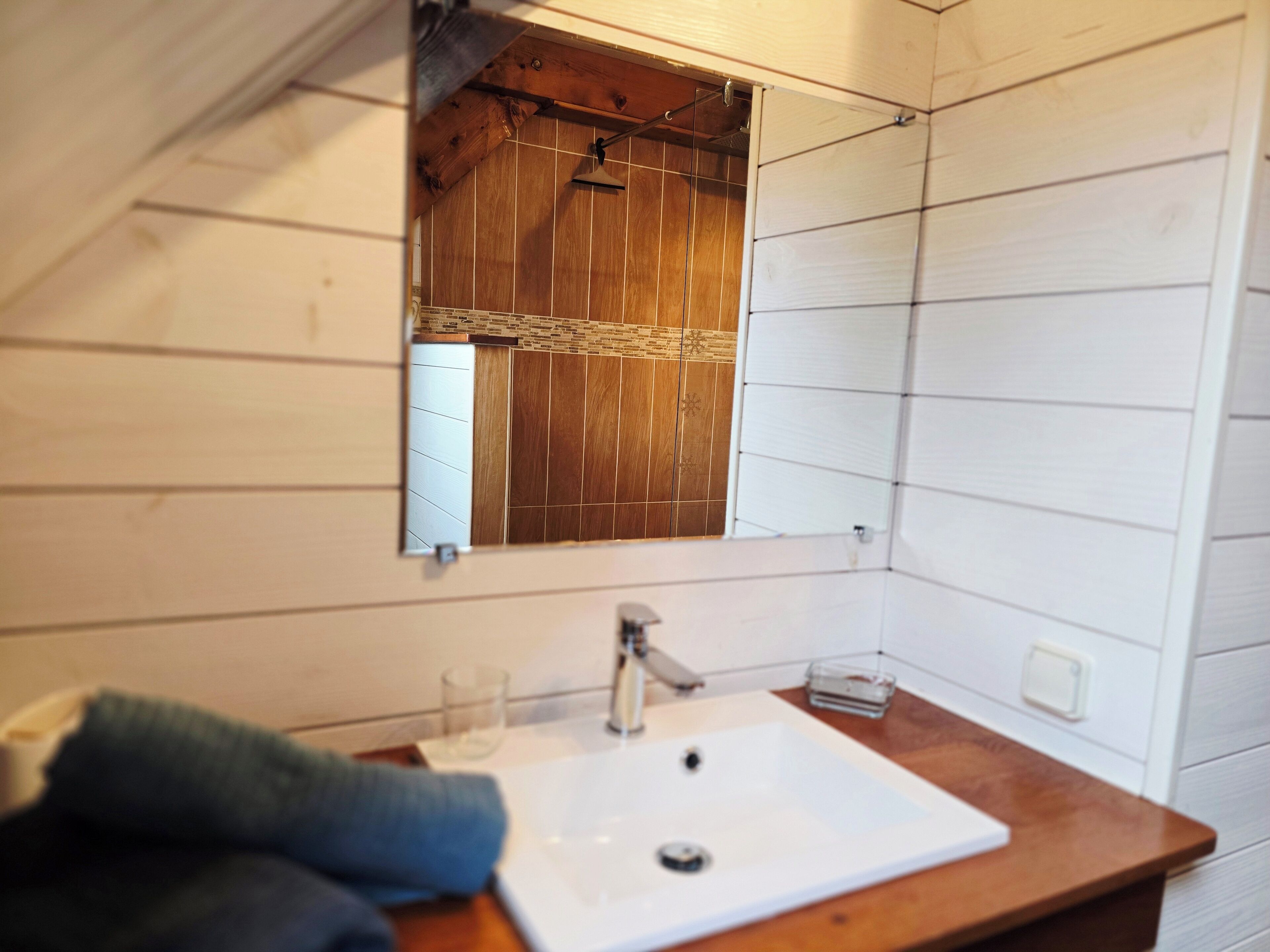 Een badkamer met een houten wastafelmeubel, een witte wasbak en een spiegel.