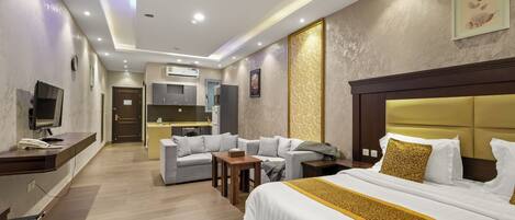 Una habitación de hotel con cama, escritorio, sofá y kitchenette.