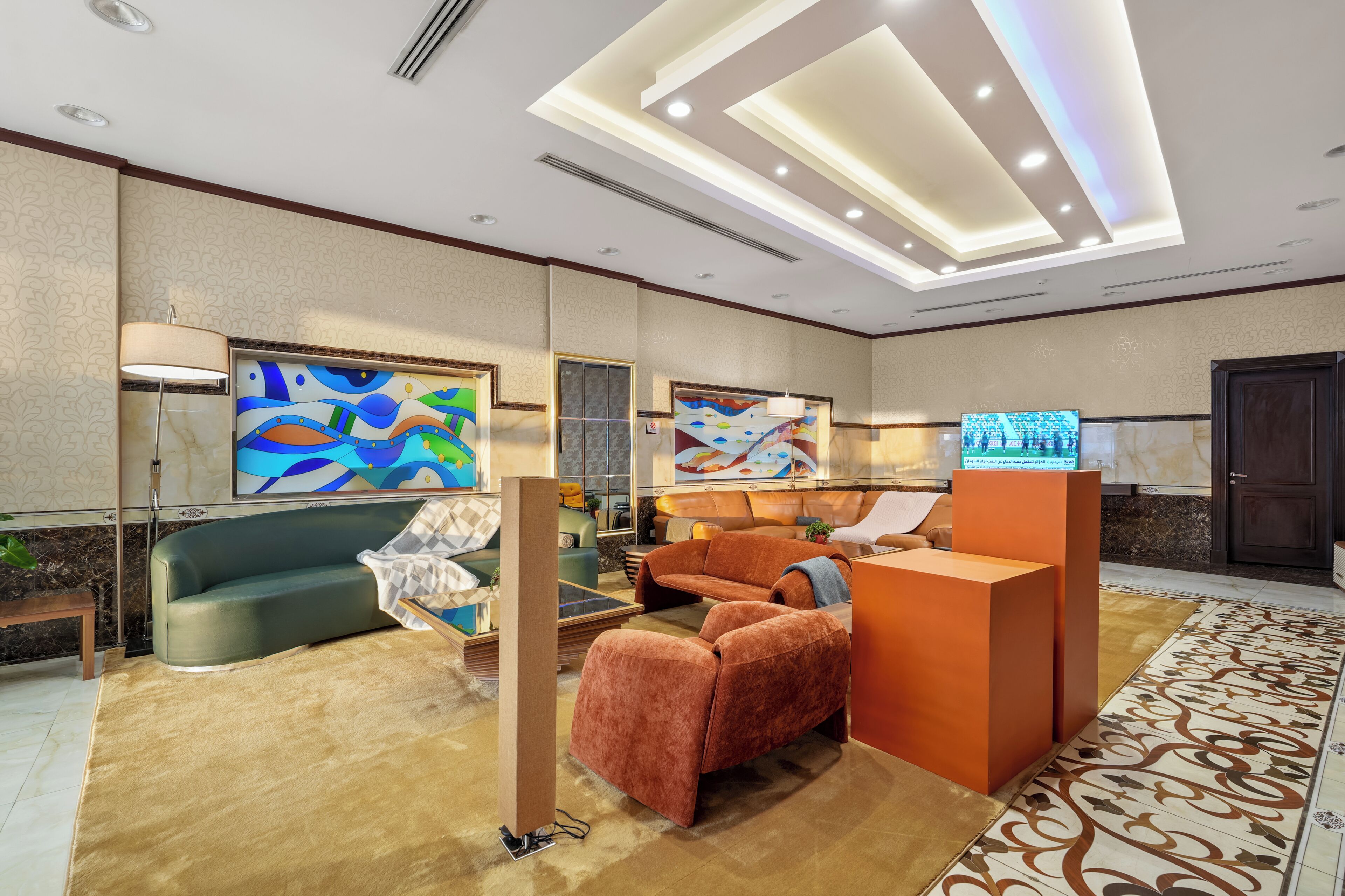 A modern lobby with a sofa, a reception desk, and abstract paintings on the walls.