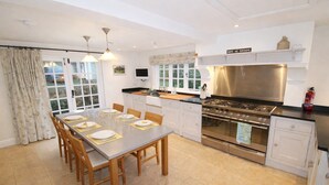 Cozinha moderna com mesa de jantar posta para quatro, fogão de aço inoxidável e armários brancos.