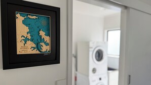 En inramad karta över nordvästra Stilla havet hänger på väggen, bredvid står en tvättmaskin, och en dörr leder in till ett annat rum.