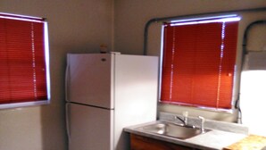 Una cocina compacta con refrigerador, pileta y armarios de madera.