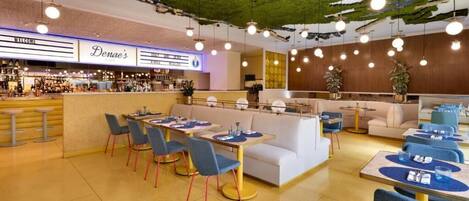 Ein modernes Restaurant mit grüner Decke, einer Bar und verschiedenen Sitzgelegenheiten.