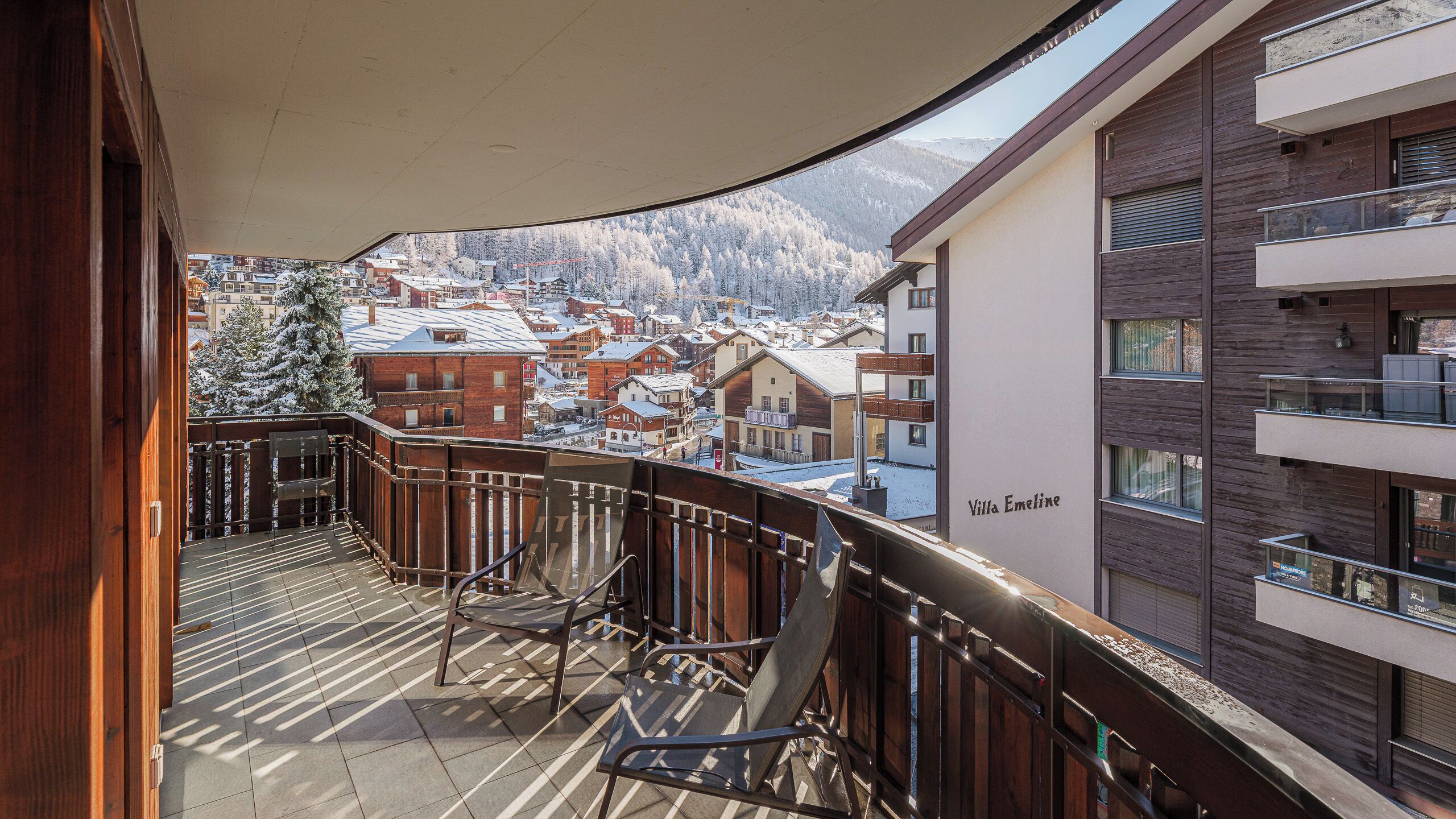 Ein Balkon mit Blick auf ein verschneites Dorf und Berge.