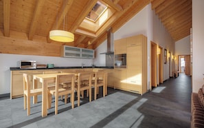 Una cucina moderna con mobili in legno, un'isola centrale con sedie, un lucernario e un lungo corridoio.