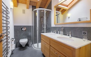 A modern bathroom with a shower, two sinks, a toilet, and a mirror. - Haus Zur Matte by Zermatt Premium (Zermatt)