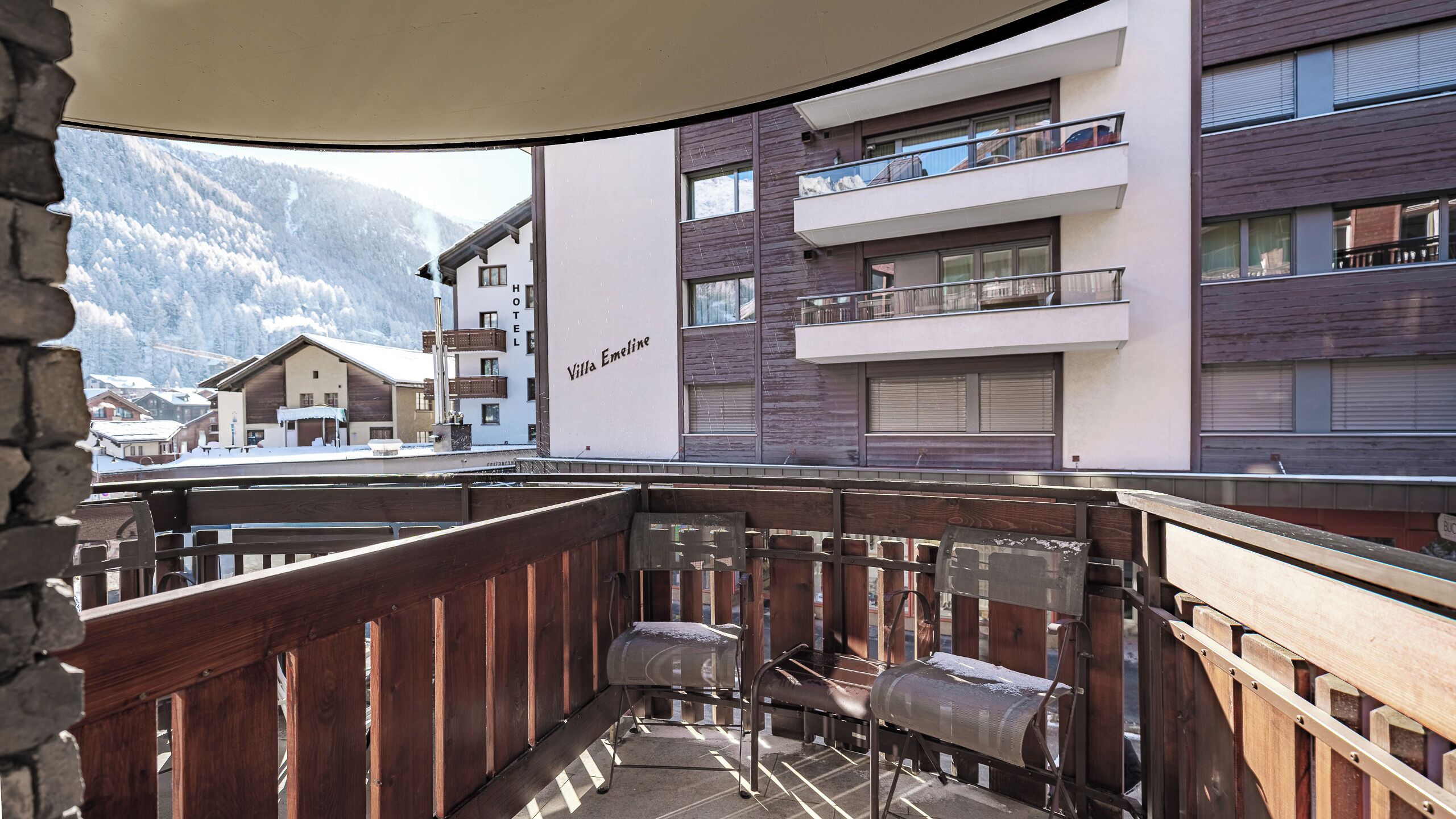 A balcony with a view of a hotel and mountains.
