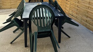 A patio with a table and chairs, surrounded by a wooden fence. - To the hillside butterfly (Magenta)