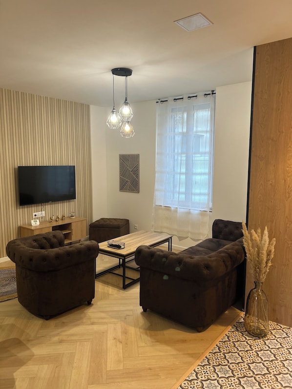 A modern living room with a flat-screen TV, two sofas, a coffee table, and a decorative vase. - To the hillside butterfly (Magenta)