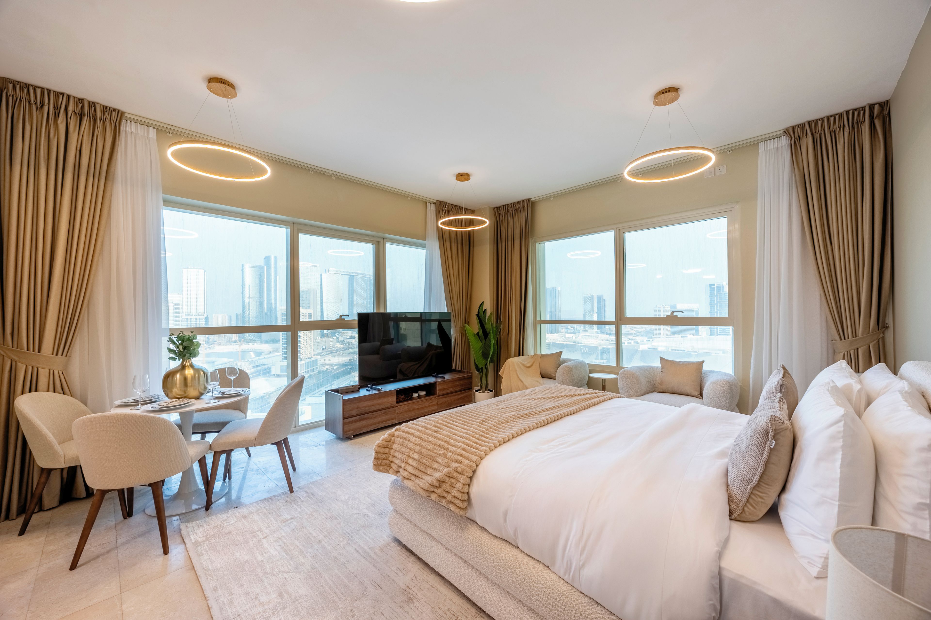 Une chambre d’hôtel moderne dotée d’un grand lit, d’une télévision, d’un coin repas et offrant une vue sur le paysage urbain.