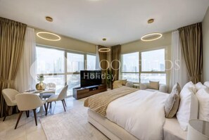 A modern hotel room with a large bed, a TV, a dining area, and large windows offering a city view. - 2202 Bloomfileds Modern STU Marina Heigh (Abu Dhabi)