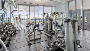 Ein Fitnessstudio mit unterschiedlichen Trainingsgeräten, großen Fenstern und Blick ins Freie.