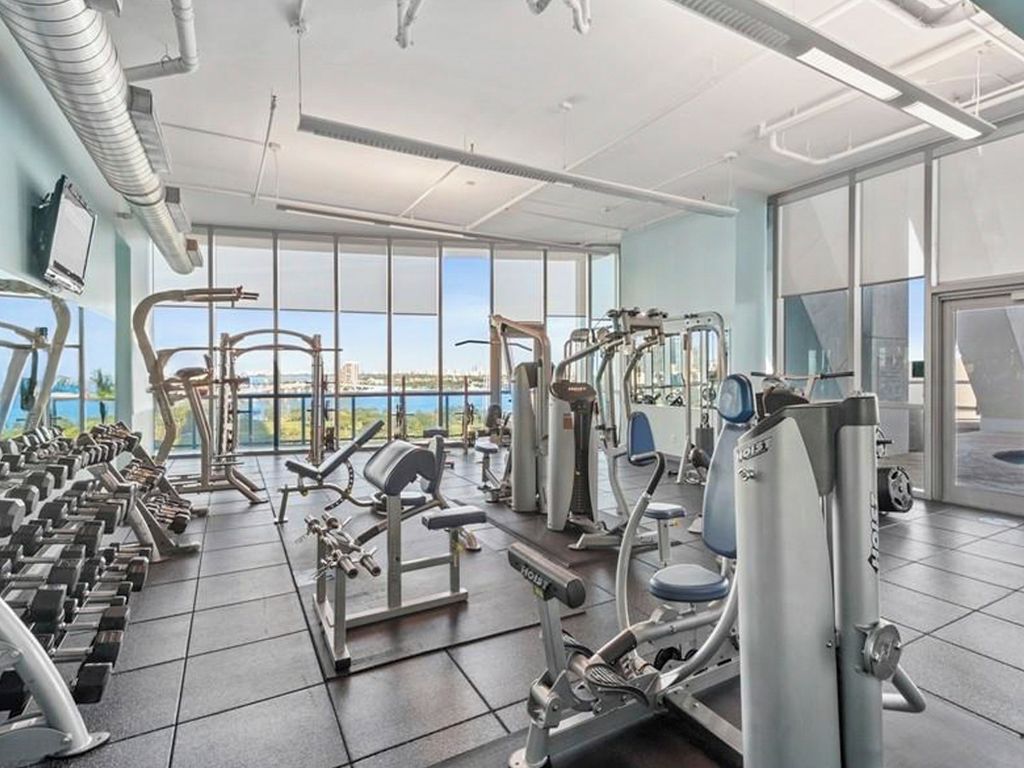 A gym with various exercise equipment, large windows, and a view of the city.