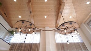 A spacious atrium with wooden ceiling beams, large windows with sheer curtains, and a central wooden chandelier with multiple light bulbs. - Escape to Amber Moon – Private Luxury Villa in Kumarhatti (Dharampur)
