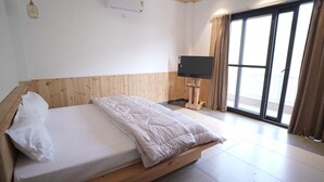 A bedroom with a wooden headboard, a bed with white bedding, a flat-screen TV mounted on the wall, and a large sliding glass door with curtains. - Escape to Amber Moon – Private Luxury Villa in Kumarhatti (Dharampur)
