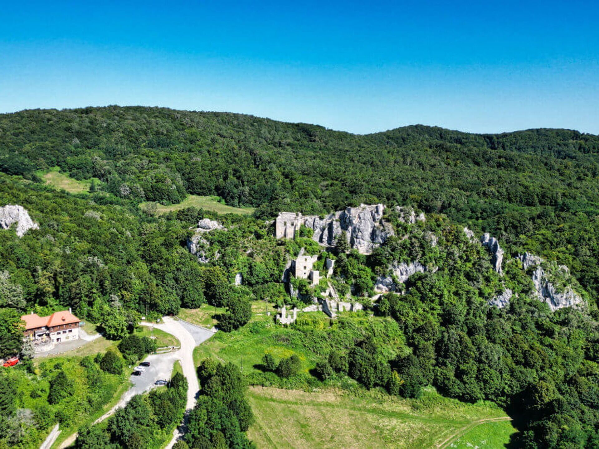 Bergachtig landschap met een klein gebouw, omringd door weelderige begroeiing en rotsformaties.