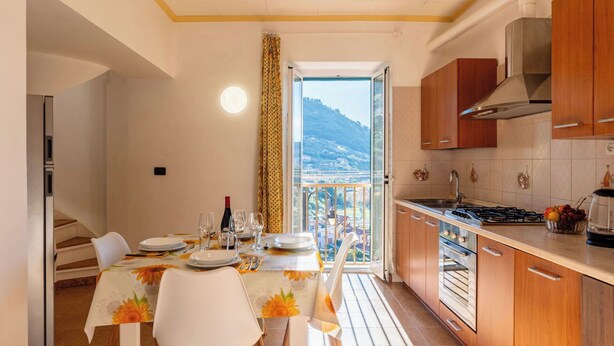 Cozinha moderna com armários de madeira, fogão a gás e área de jantar com mesa posta para quatro.
