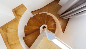 Escada espiral com degraus de madeira e corrimão branco.
