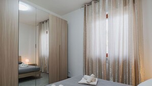 A hotel room with a bed, a mirror, and curtains. - Lovely apartment for 6 guests with WIFI, A/C, TV and patio (Viareggio)