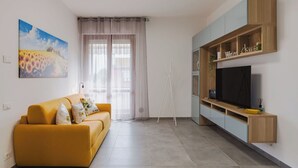 A modern living room with a sofa, TV, and built-in shelving. - Lovely apartment for 6 guests with WIFI, A/C, TV and patio (Viareggio)