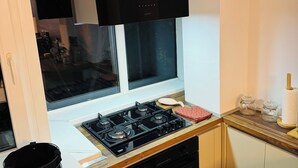 Cocina compacta con estufa a gas, horno y campana extractora negra.
