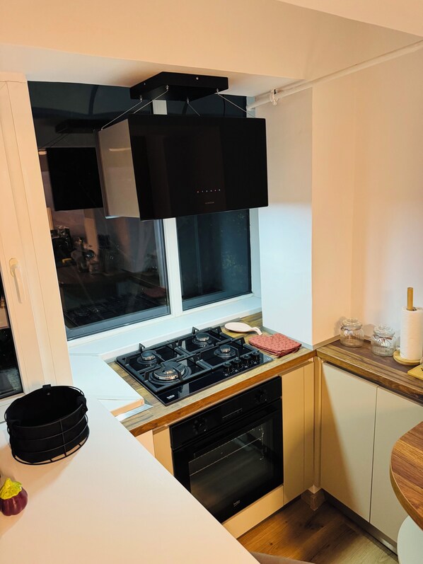 Cocina compacta con estufa a gas, horno y campana extractora negra.