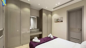 Ein modernes Hotelzimmer mit einem großen Bett, einem Kleiderschrank, einem Schminktisch mit Spiegel und einer Tür.